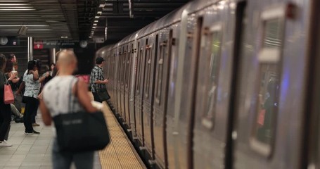 People standing by the subway train waiting for the metro to come to a full stop at their subway platform station