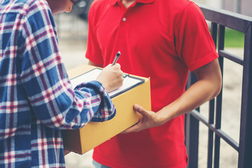 Young man Delivering Package to customer at home. Delivery - obrazy, fototapety, plakaty