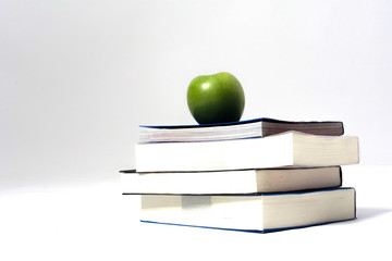 Pile of books with green apple white background