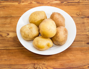 Potatoes boiled in their skins on dish on wooden surface