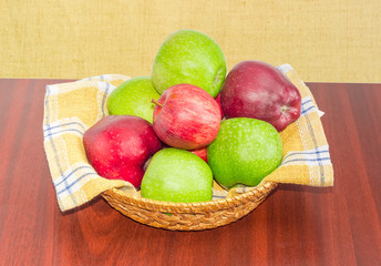 Red and green apples on checkered napkin in wicker basket