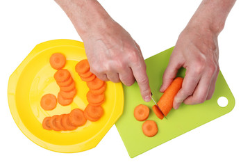 Chef elderly grandpa  with a knife and hands is cut orange carrots into round pieces.