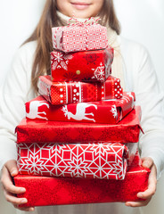 Young woman with pile of packed christmas gifts on white background