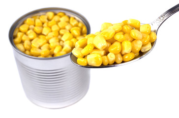 Pile of a canned corn and a spoon over it, composition isolated