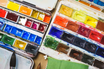 Top view from above on a palette of watercolors prepared by the artist for drawing. Brushes and...