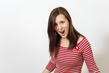 Pretty European young angry brown-haired woman with healthy clean skin, dressed in casual red and grey clothes, screaming, swearing and waving her arms, on a white background. Emotions concept.