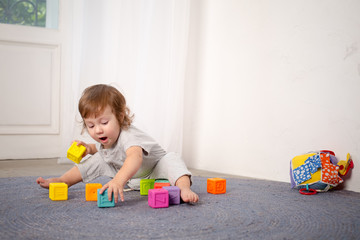 Little happy girl playing with toy on floor. Kindergarten.