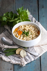 Homemade chicken soup with homemade noodles on an old wooden table..