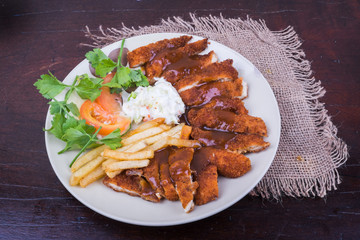 Top view of  chicken chop with vegetable and black pepper sauce in plate over wooden table