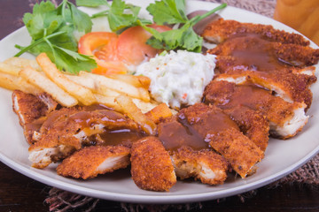 Chicken chop with vegetable and black pepper sauce in plate over wooden table