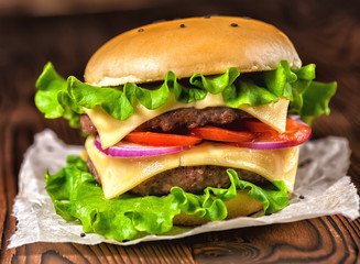 homemade burger with vegetables, spices and beef meat on dark wooden background