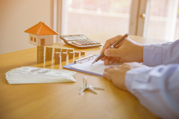 man signing paperwork, new home in background