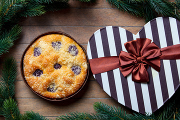Christmas pie and gift boxes around on wooden table.