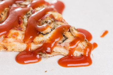 Closeup macro of pizza slice with ham mushrooms and ketchup on the white marble
