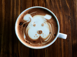 Cute dog face latte art coffee in white cup on wooden table ; cute dog latte art in your cup , love dog love coffee