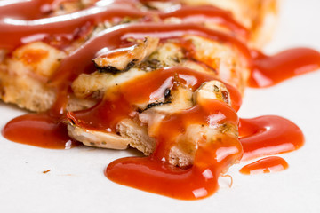 Closeup macro of pizza slice with ham mushrooms and ketchup on the white marble