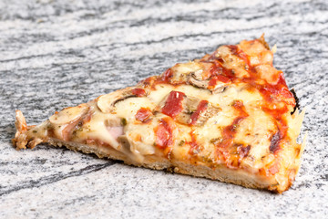 Pizza slice with mushrooms ham cheese and ketchup on the grey granite background