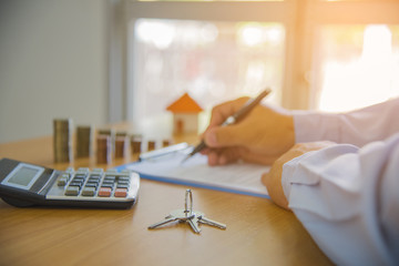 man signing paperwork, new home in background