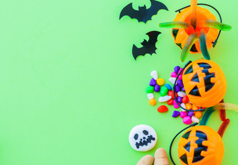 Halloween pumpkin with sweets candies on green background.