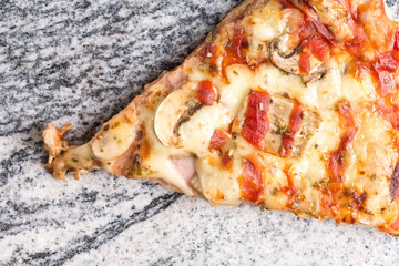 Pizza slice with mushrooms ham cheese and ketchup on the grey granite background