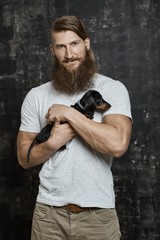Muscular bearded man holding little dog