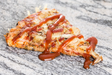 Pizza slice with mushrooms ham cheese and ketchup on the grey granite background