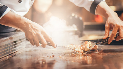 Fototapeta premium Hand of man take cooking of meat with vegetable grill, Chef cooking wagyu beef in Japanese teppanyaki restaurant