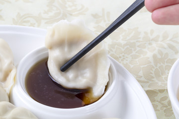 Closeup dumpling with chopsticks and sauce.