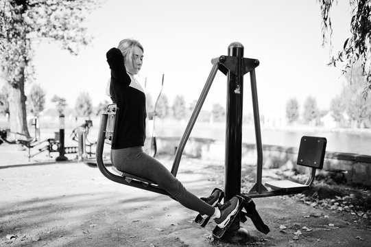 Young girl has the training and doing exercise outdoors on street simulators. Sport, fitness, street workout concept.