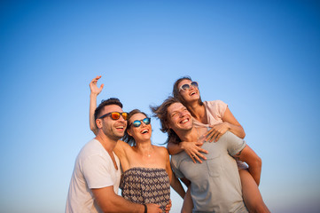 Four cheerful young people against the background of the blue sky.