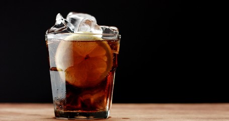 Cocktail with cola and limes slices isolated on blackbackground