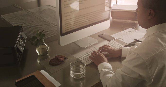 mixed race businessman working with computer. White shirt, smartphone