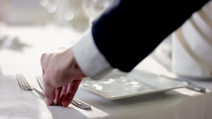 Shot of waiter hand preparing the dinner table before celebration at restaurant