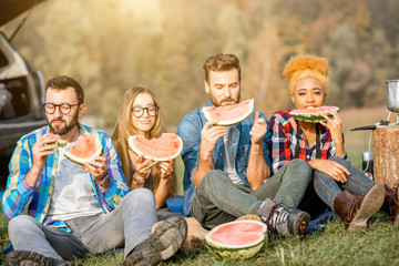 Multi ethnic group of friends having a picnic, eating watermelon during the outdoor recreation