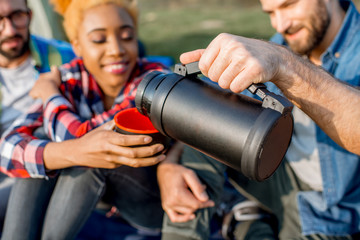 Friends pouring tea with hiking thermos during the outdoor recreation