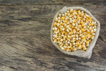top view of dried corn seeds in a sack on old and crack wooden board with copy space for text.