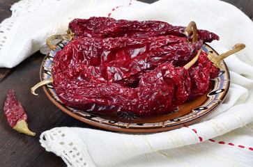 Obraz premium Dried big red peppers on a ceramic plate ,on a wooden background