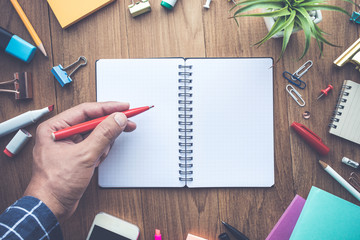 Top view of male hand writing on notepad and office supplies.business creativity and inspiration concepts