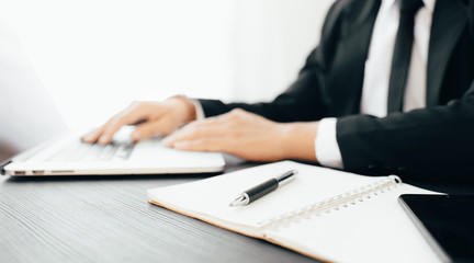 Side view shot of a man's hands using smart phone in interior, rear view of business man hands busy using cell phone at office desk