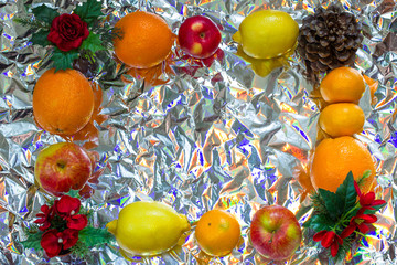 Christmas frame of citrus, cones and Christmas red flowers on a shiny background. Oranges, tangerines, lemons, bumps and apples, as a symbol of Christmas.