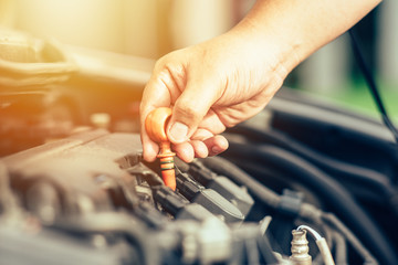 Mechanic repairing car with open hood,Side view of mechanic checking level motor oil in a car with open hood