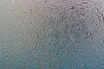 Water drops on window glass against the sky in the sun 