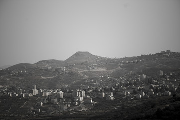 atmospheric black and white photo of the city quarters of Jerusalem surrounded by high hills