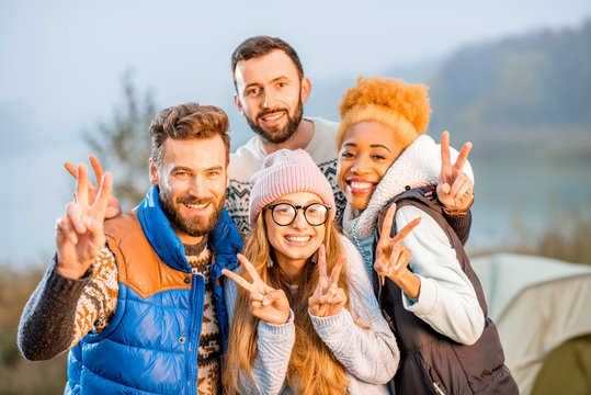 Close-up Portrait Of Multi Ethnic Group Of Friends Dressed In Sweaters Hugging Together And Warming Up At The Camping During The Evening