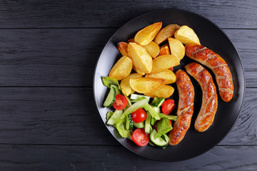 grilled sausages, baked potatoes, vegetables salad