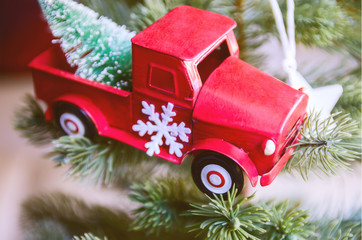 Miniature red car with a Christmas hangs on the fir tree. Concept for Merry Christmas  and Winter holidays.