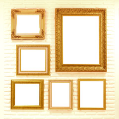 empty golden picture frames on brick wall