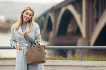 Young woman in blue coat. Autumn city background.