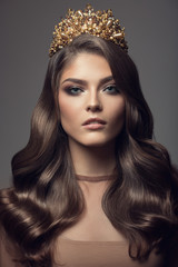 Beautiful woman in gold crown on her head. Long wavy brown hair.