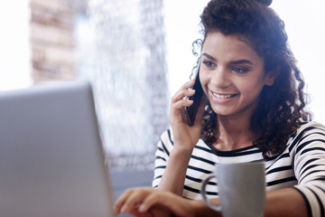 Happy curly-haired girl talking on the phone